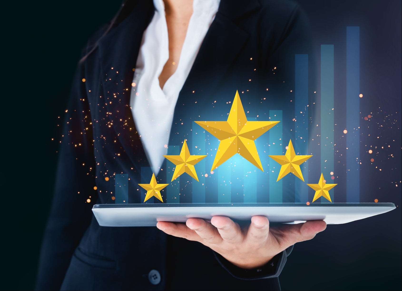 Person holding a tablet with five gold stars above it on a dark background