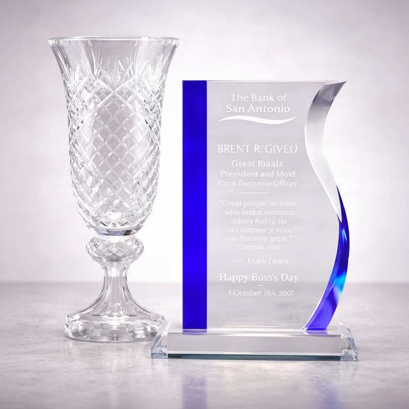 Clear glass vase and personalized glass award on a reflective surface with a light gray background